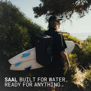 Surfer carrying the SAAL Surfpack and a surfboard on a coastal trail