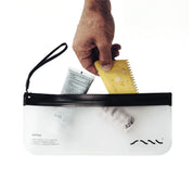 Hand packing sunscreen and surf wax into the translucent SAAL Surf Stash pouch